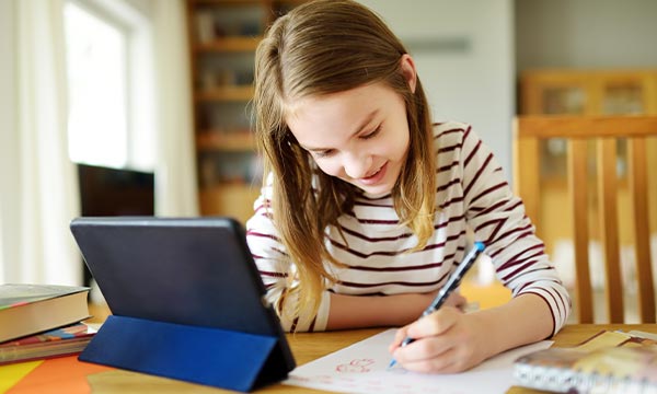 Girl sat at home remote learning on a tablet
