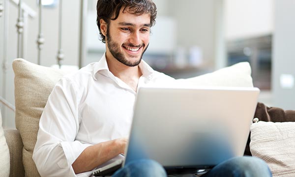 man smiling at laptop while working from home