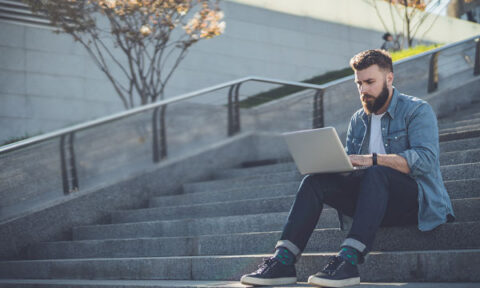 Image of a student working on a laptop alone on an empty outdoor staircase