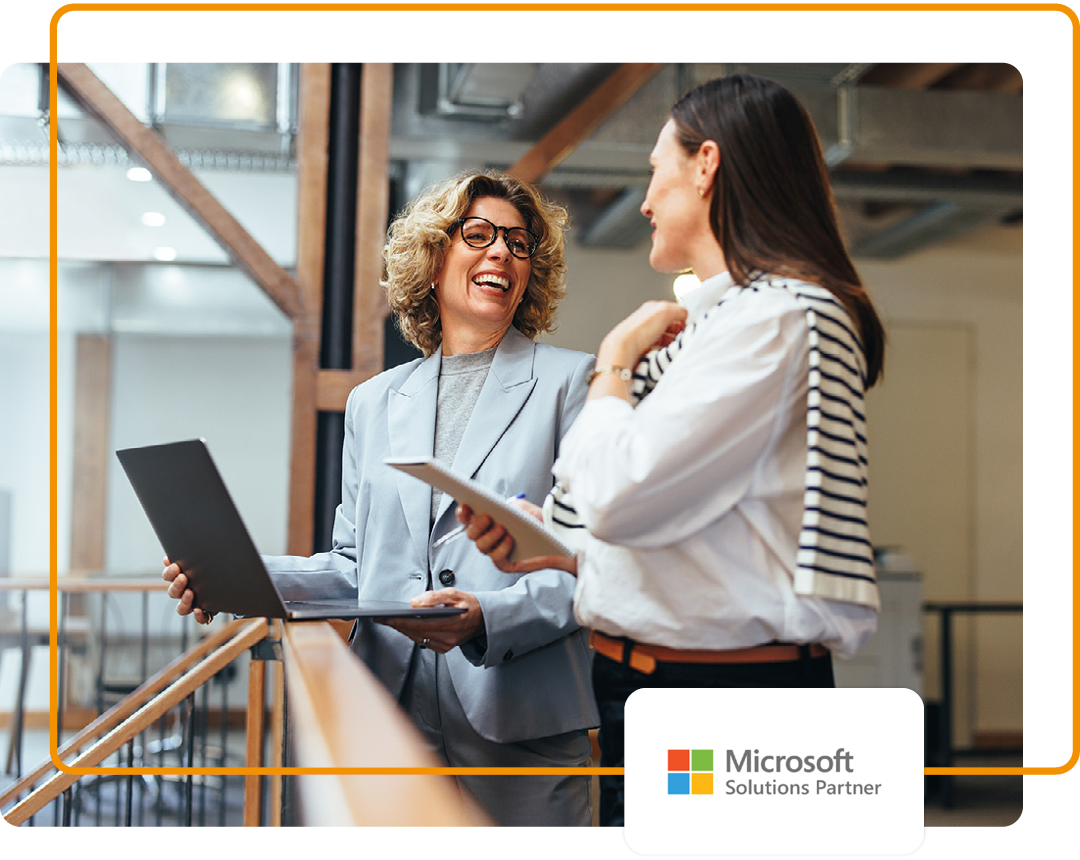 Image of two colleagues conversing in an office with our Microsoft Solutions Partner logo