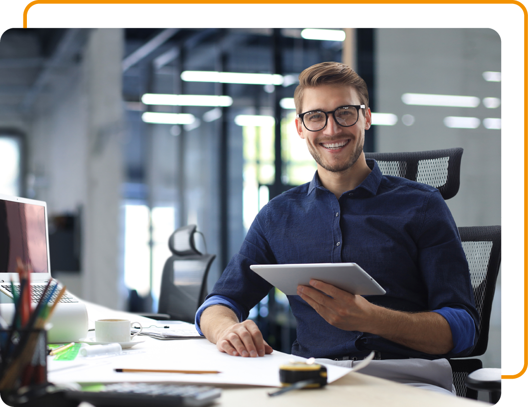 Image of a smiling person sat at a desk holding a tablet