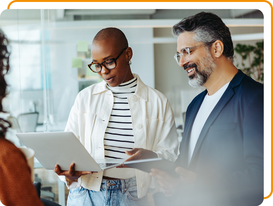 Image of two business professionals stood working on a laptop