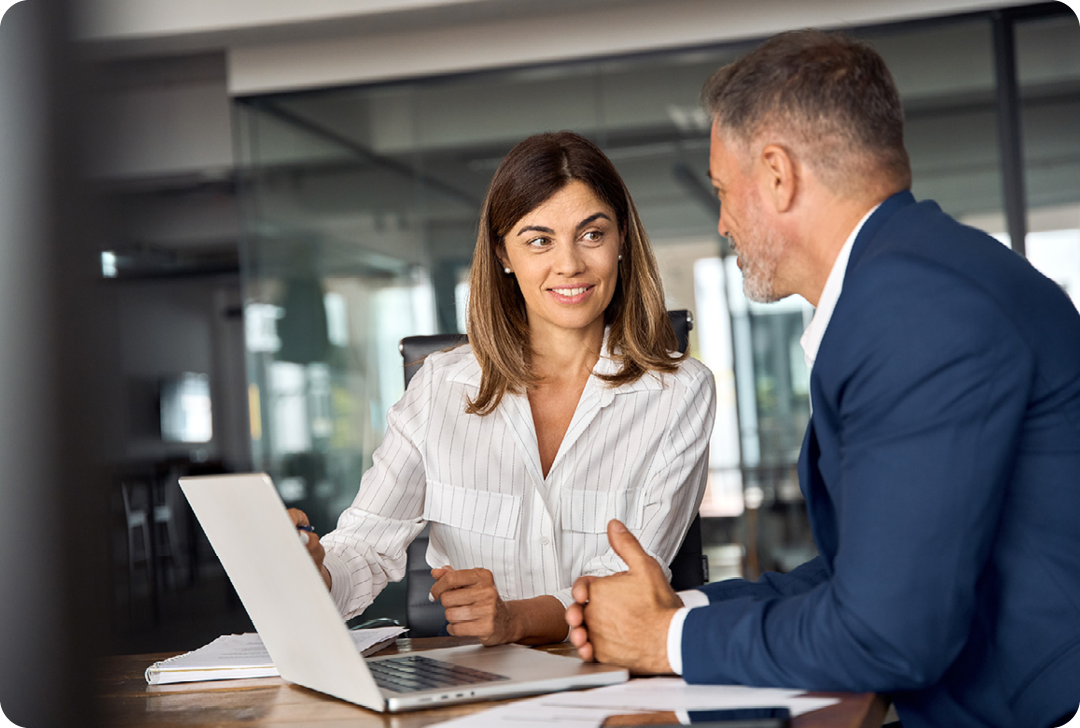 Image of two people reviewing some data on a laptop screen in an office