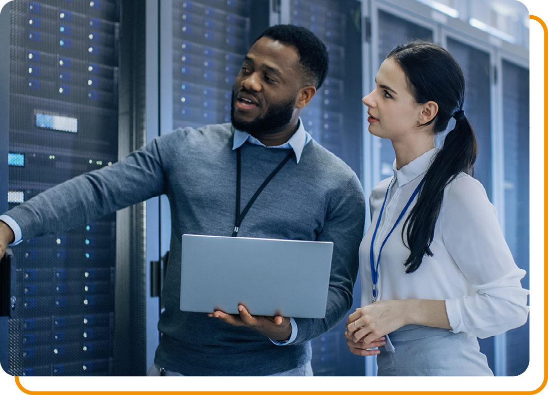 Image of two IT professionals walking around a server room with a laptop