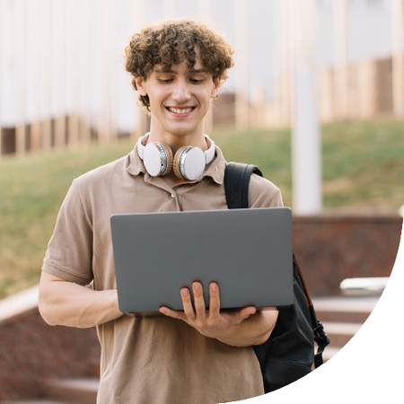 Image of a student on a campus holding a laptop