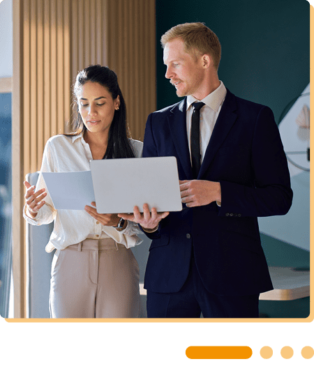 Image of two colleagues walking in an office with laptops
