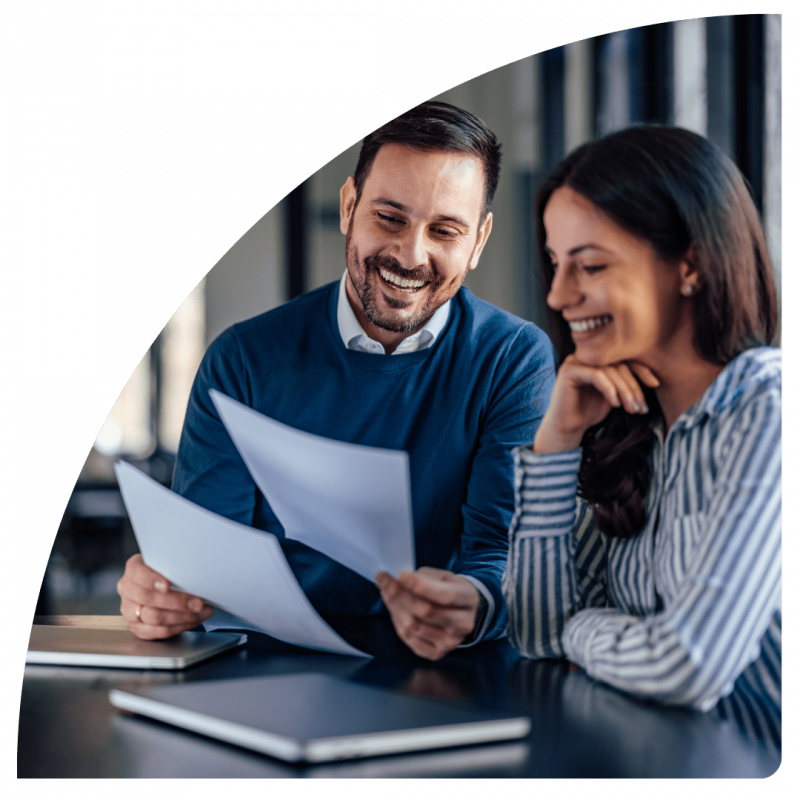 two people sat at desk smiling at work