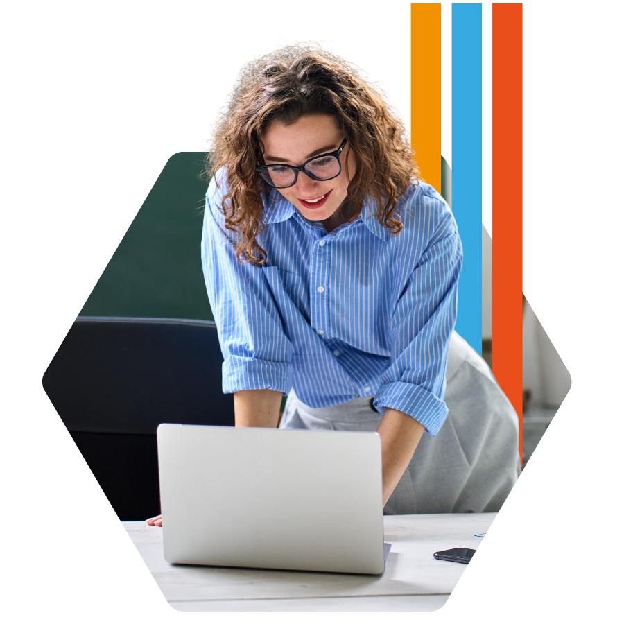 teacher standing at desk in classroom working on computer