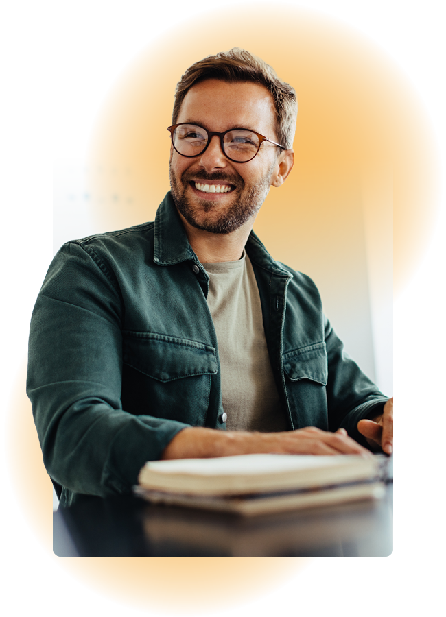 Man smiling while taking notes at a desk